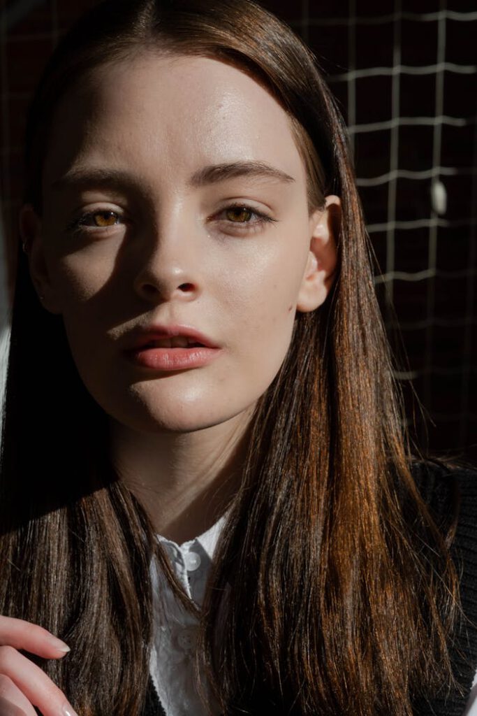 Captivating close-up portrait of a young woman with long hair, highlighted by soft sunlight.